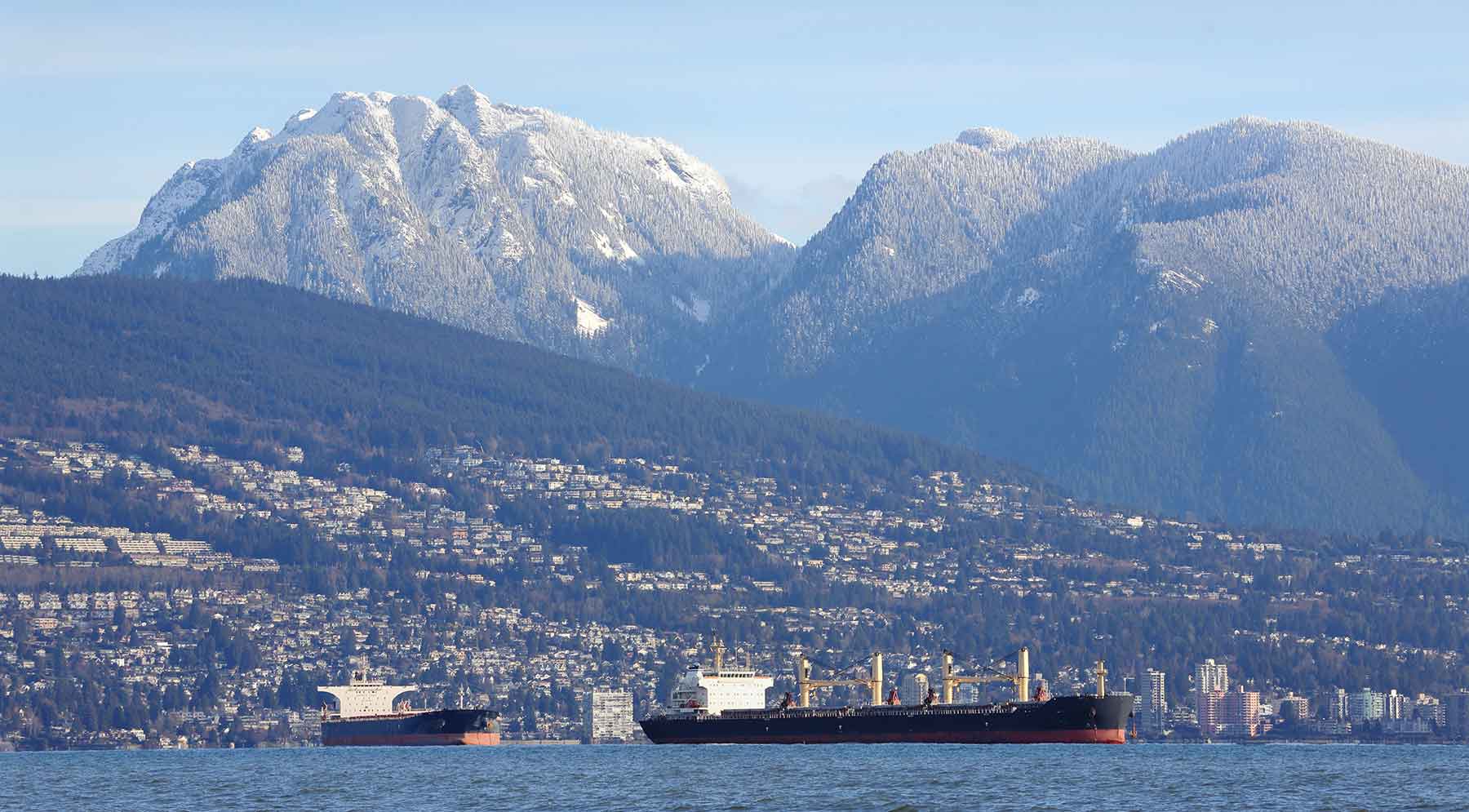 cargo vessel waiting in vancouver port with mountains in the background