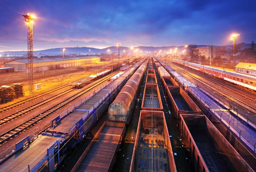 rail yard with multiple cars awaiting departure at night